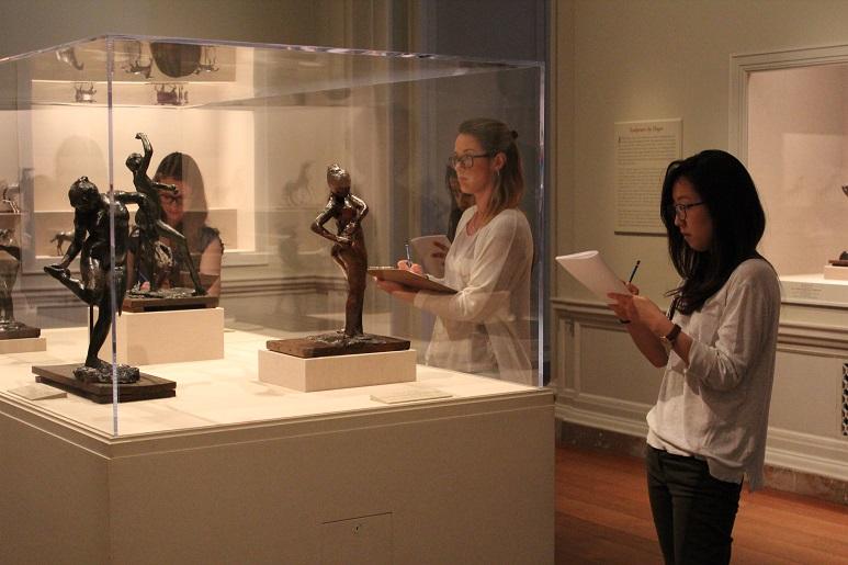 Students draw what they see in a museum case filled with artifacts