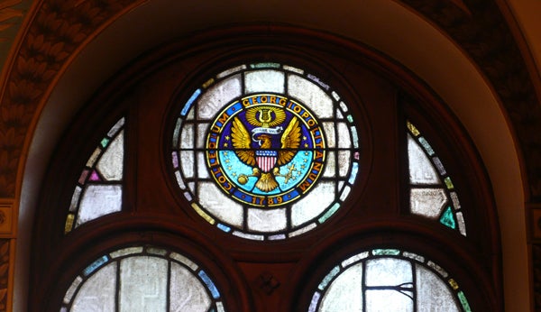 Georgetown University Seal in a stained glass window frame.