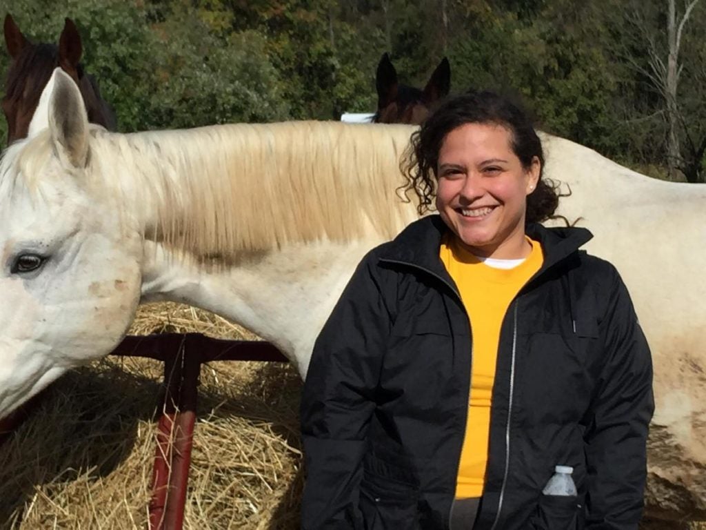 A female medical student stands by a horse