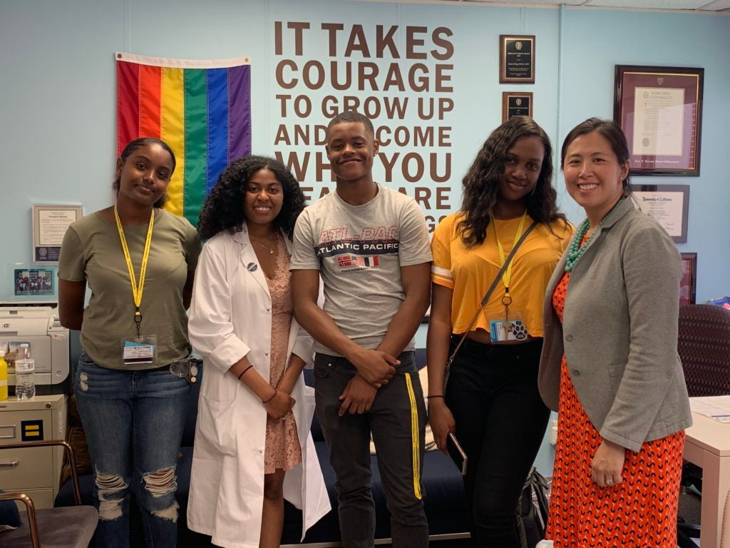 Students and a medical student stand with former dean Susan Cheng in her office
