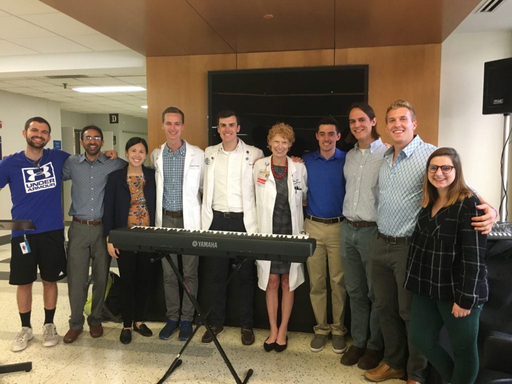 A group of students stands in a hallway behind a keyboard