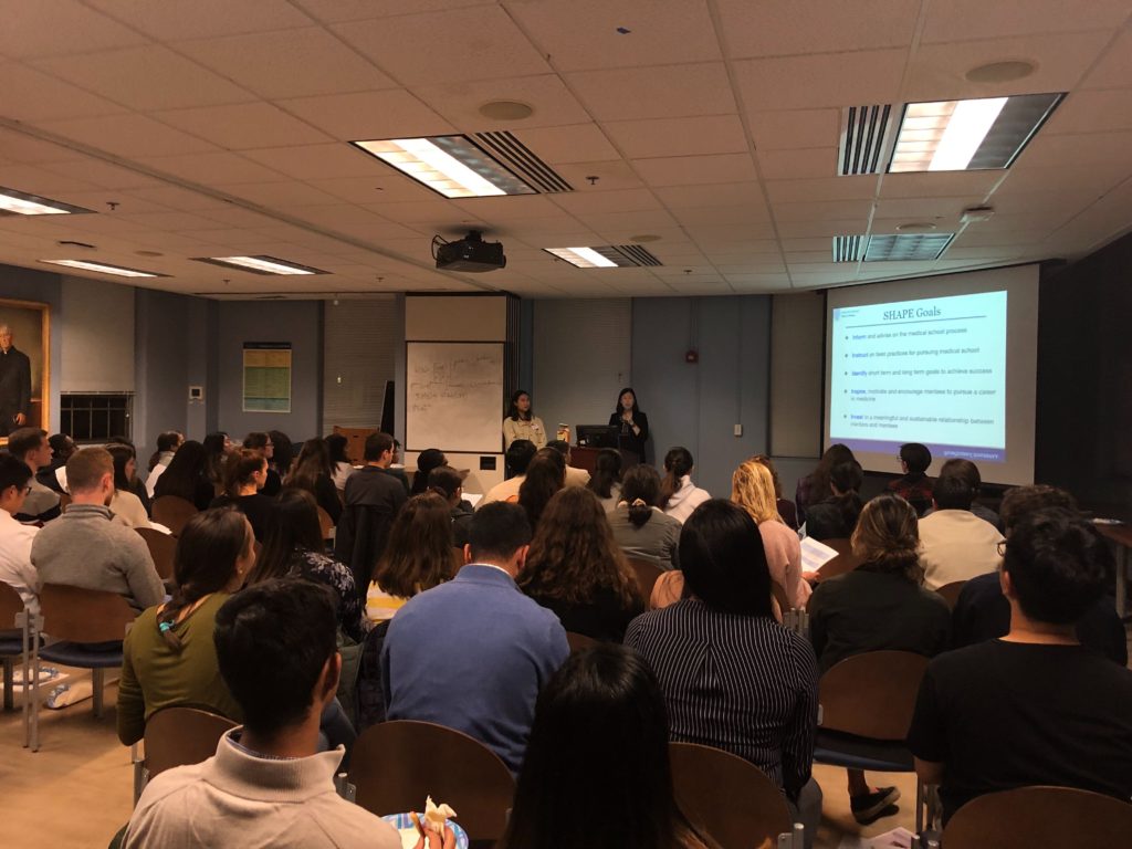 A group listens to a presentation on a screen in a classroom