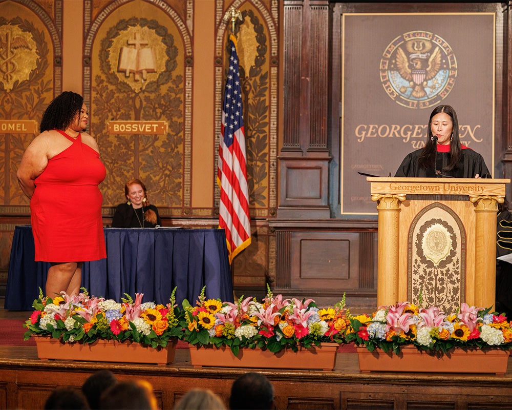 Mia Jenkins stands next to Dean Cheng as she reads her award announcement onstage