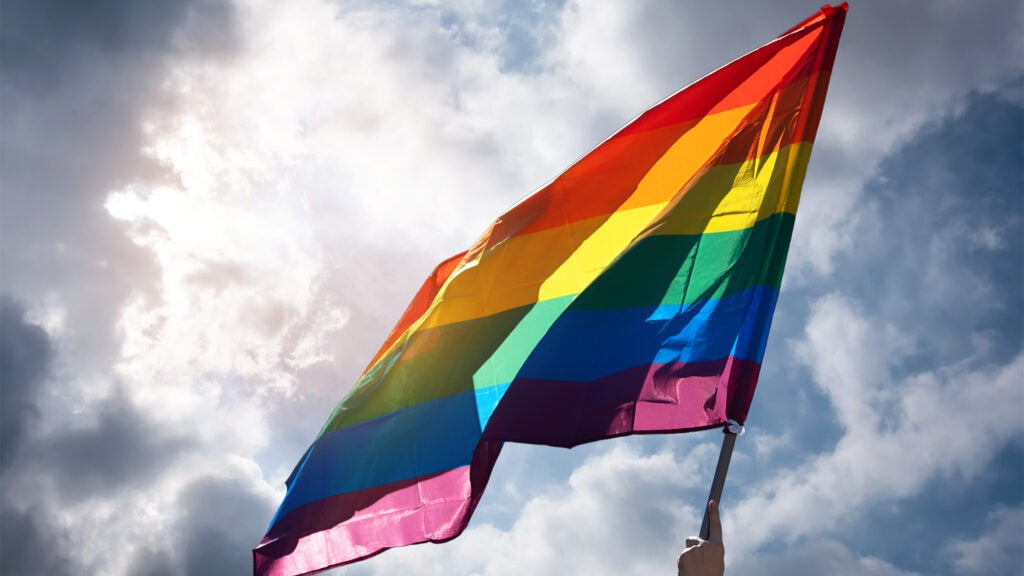 Pride flag against a blue sky