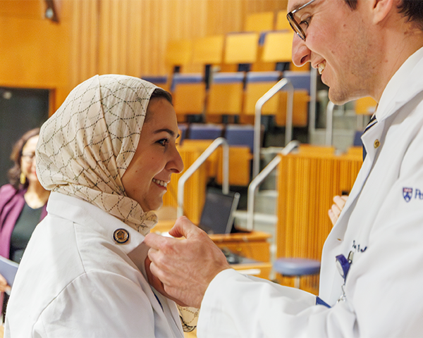 Timothy Goblirsch reaches for the lapel of Ruba Omeira's white coat