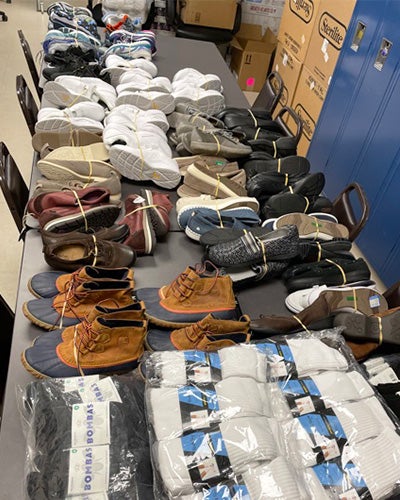 A table lined with pairs of shoes, boots and socks