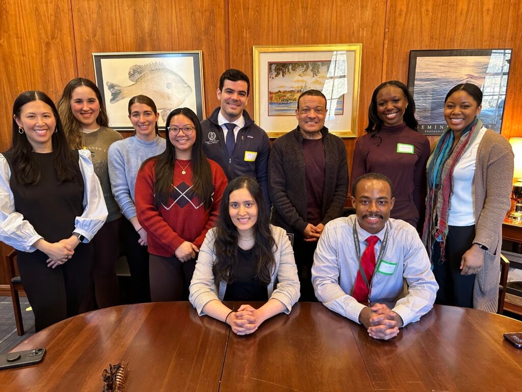 A group of students and faculty stand together in an office setting