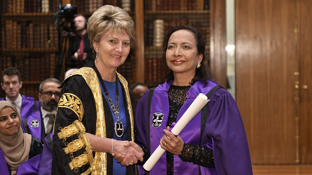 Princy Kumar holds her award and shakes the hand of the presenter