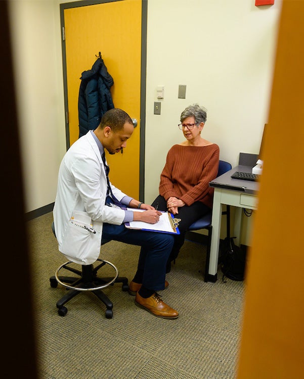 A student interacts with a standardized patient in a simulated exam room