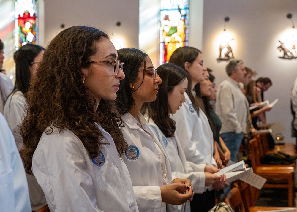 Several medical students wearing white coats show their reverence during the Donor Mass ceremony