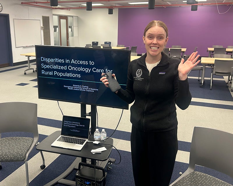 Amanda Foshag stands next to the monitor displaying her presentation