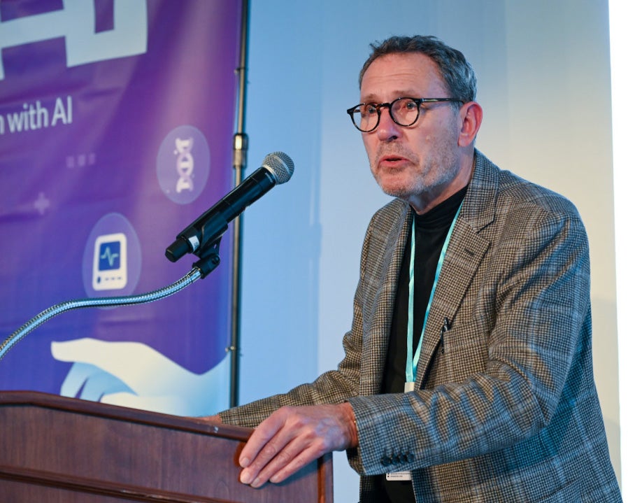 Richard Schena speaks from a podium during the hackathon