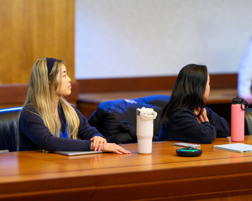 Students sit at a table and listen to Beauchamp speak