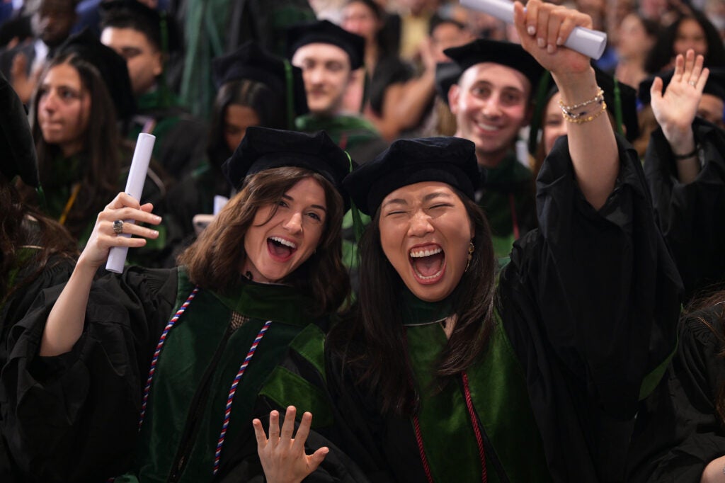 Two female students cheer with open mouths and raised arms