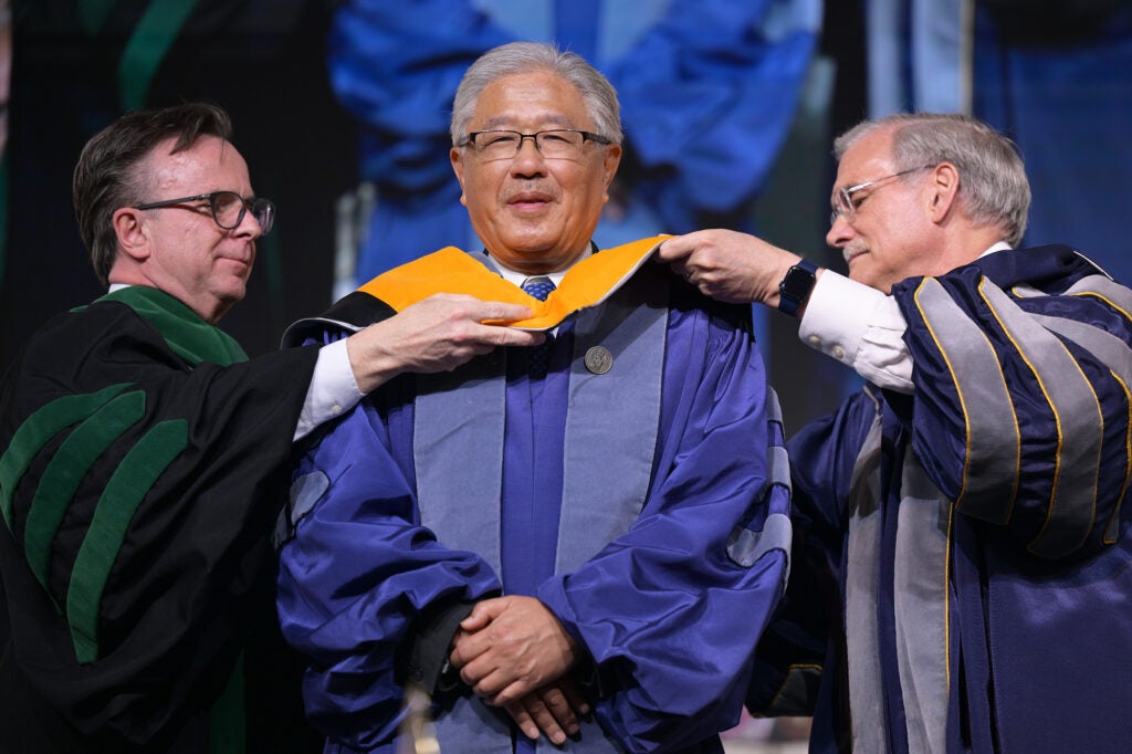 Norm Beauchamp and Bob Groves place an academic hood over Victor Dzau's head