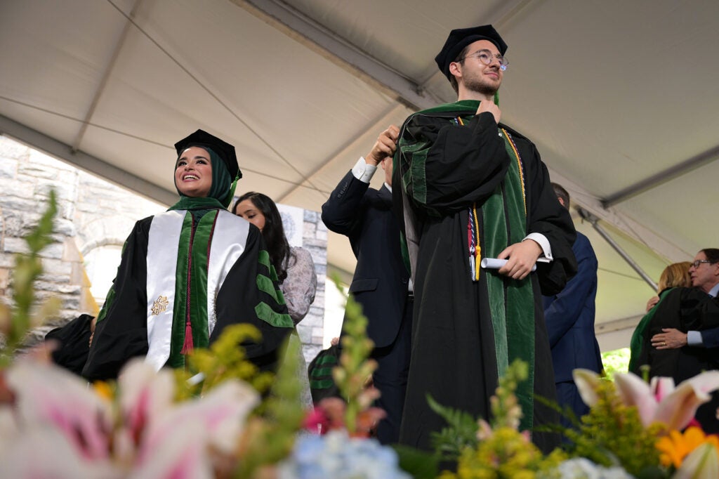 Two students onstage receive their hoods