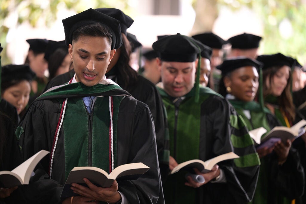Students stand in a line, each reading from a book