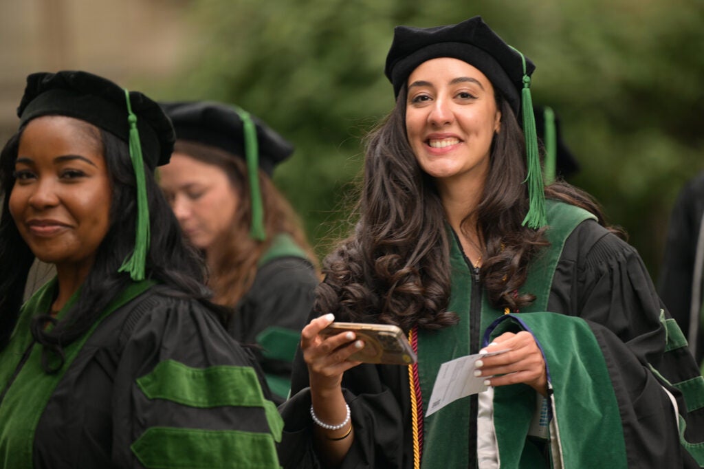 Two female students smile as they walk to commencement