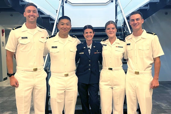 Five individuals stand together wearing military uniforms