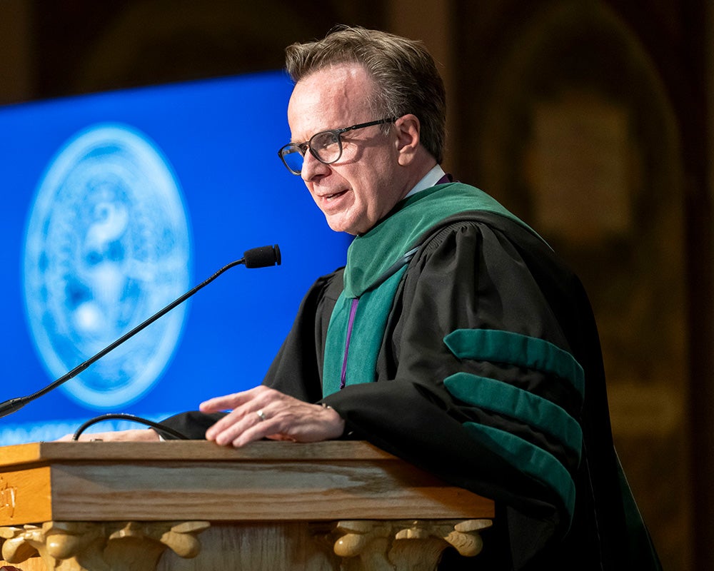 Norman Beauchamp speaks from a podium dressed in academic regalia