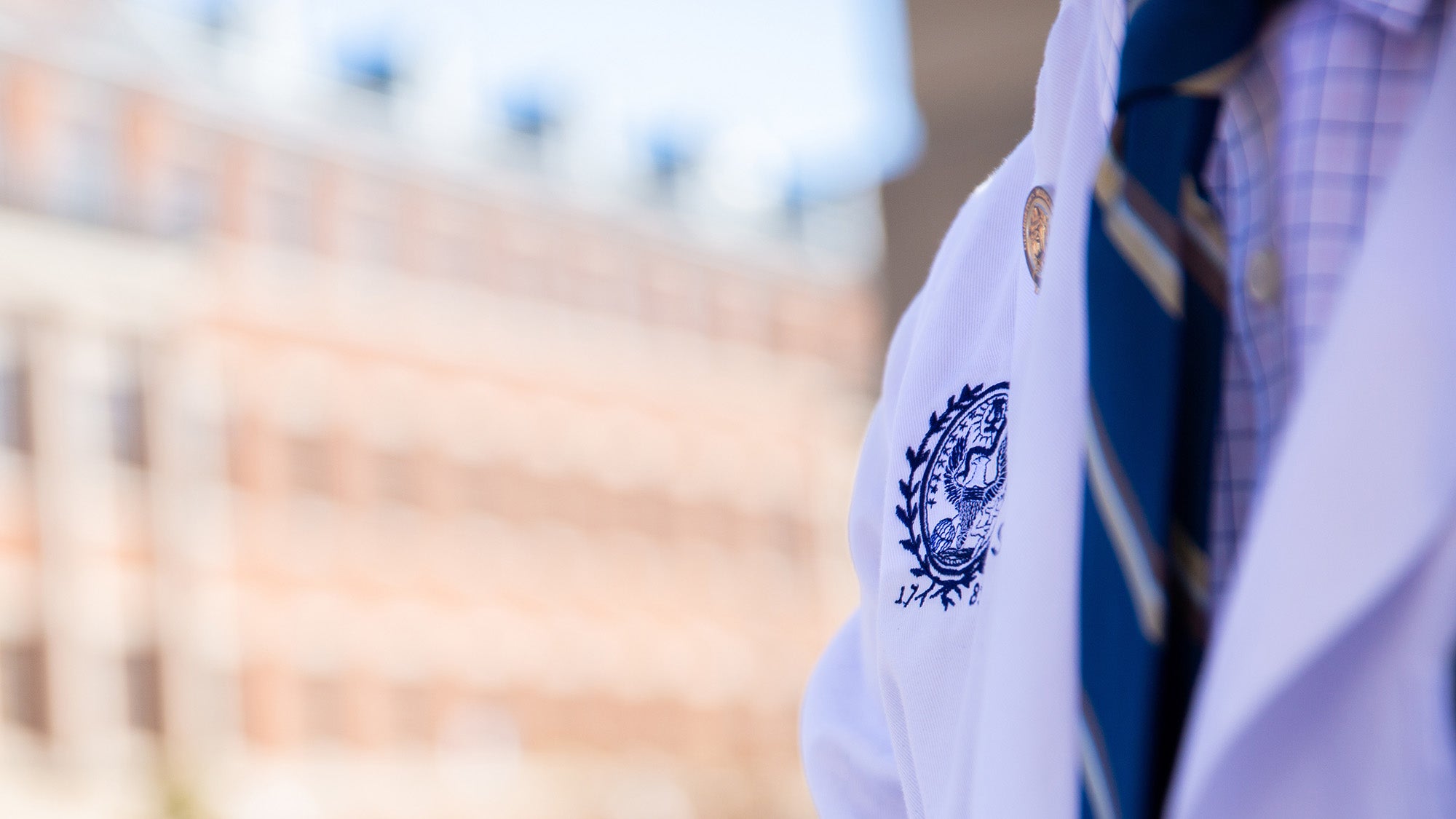 Closeup of a white coat on a student walking outside the Med-Dent building