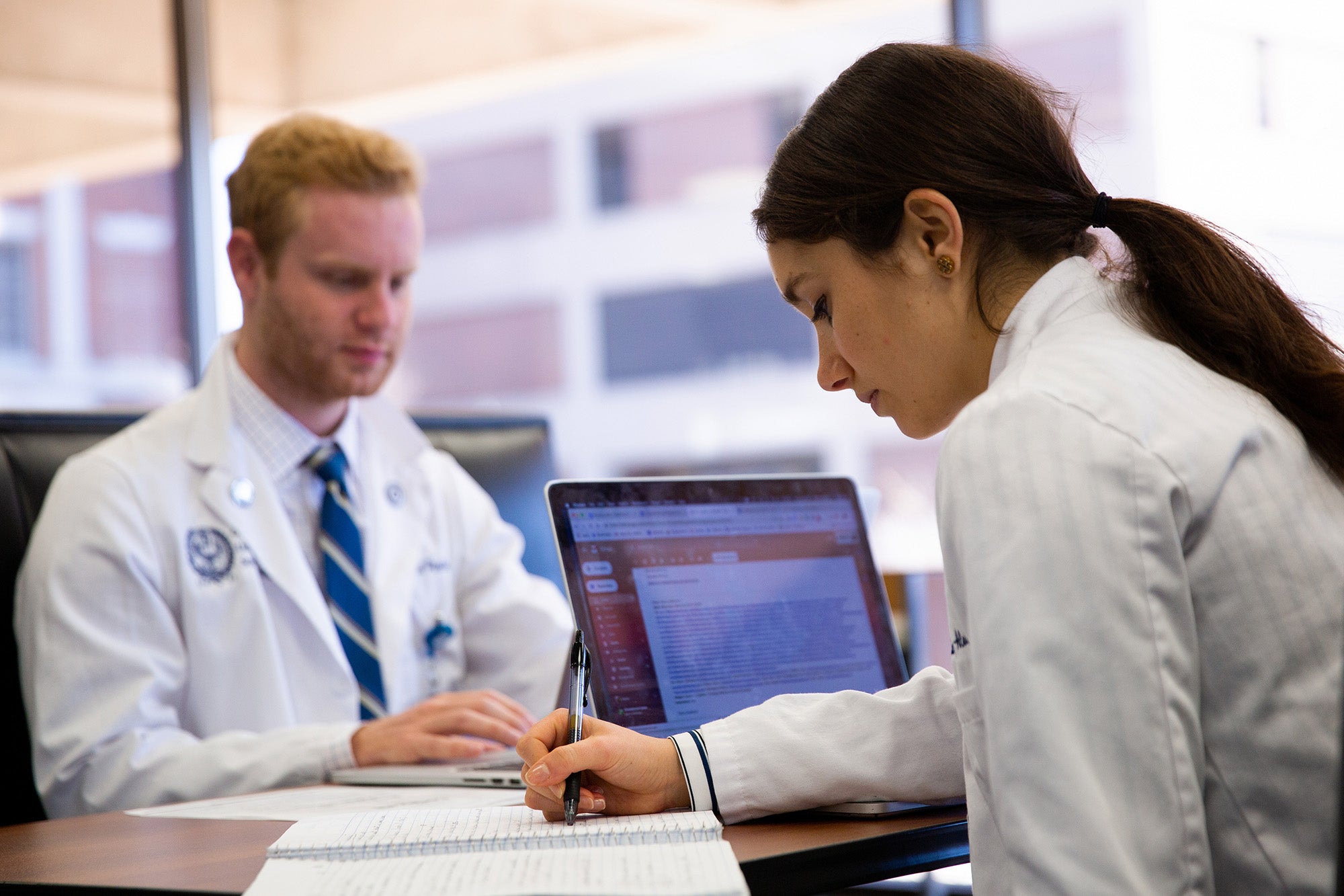 Two med students sit at a table studying