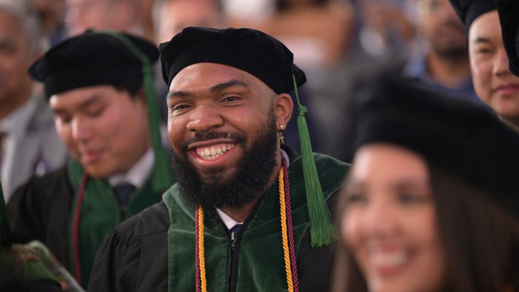 Medical students in academic regalia stand at a commencement