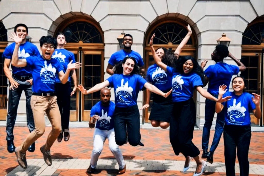 Students in a class of ARCHES jump in the air and smile