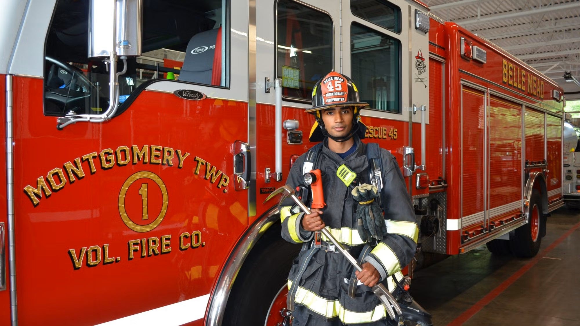 A student stands in firefighting gear in front of a fire engine