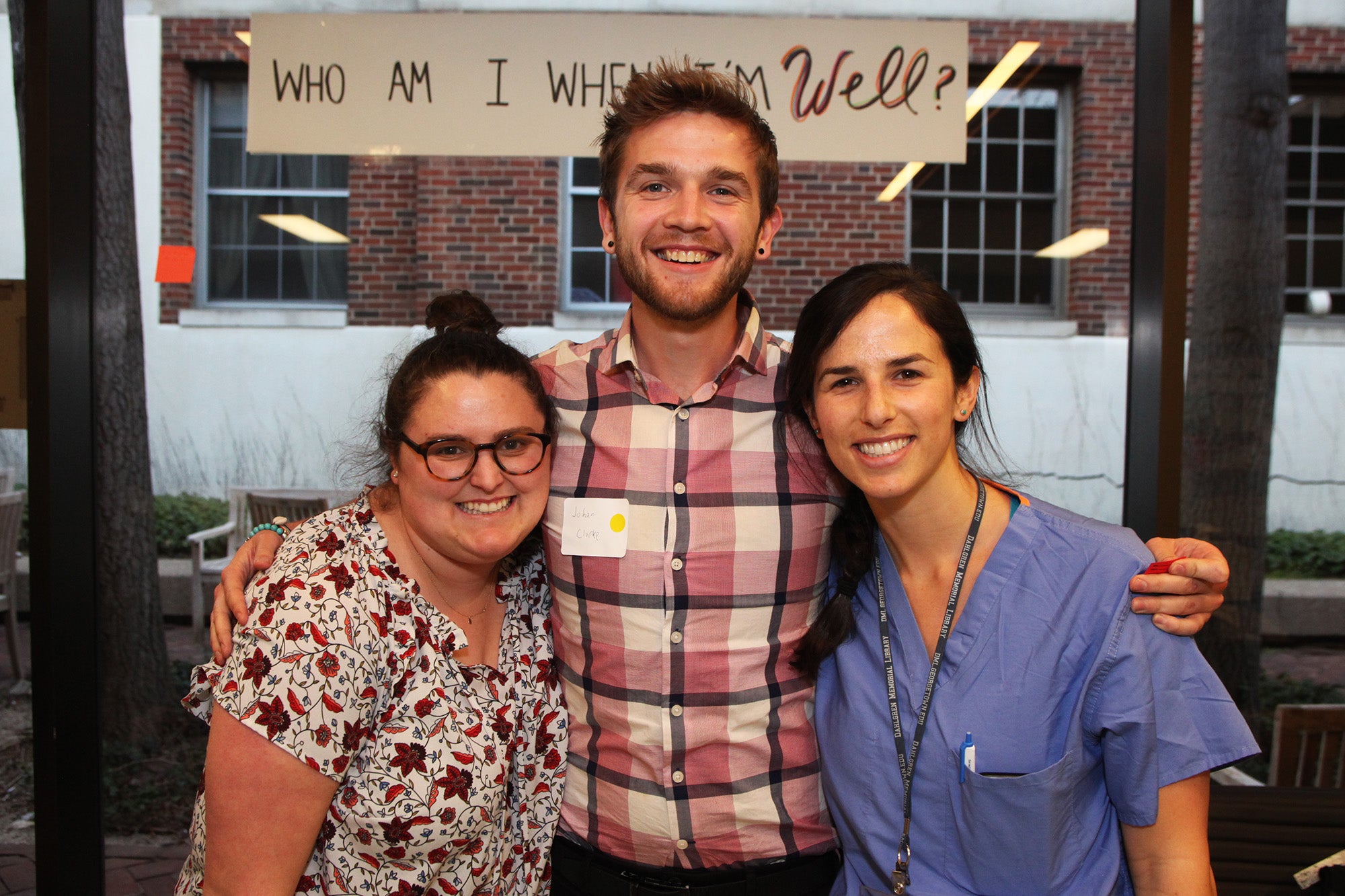 Three people stand in front of a banner at a wellness event