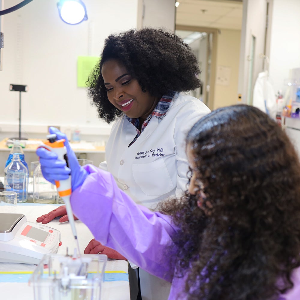 Martha Gay looks on as student Taleyah Evans works with lab equipment
