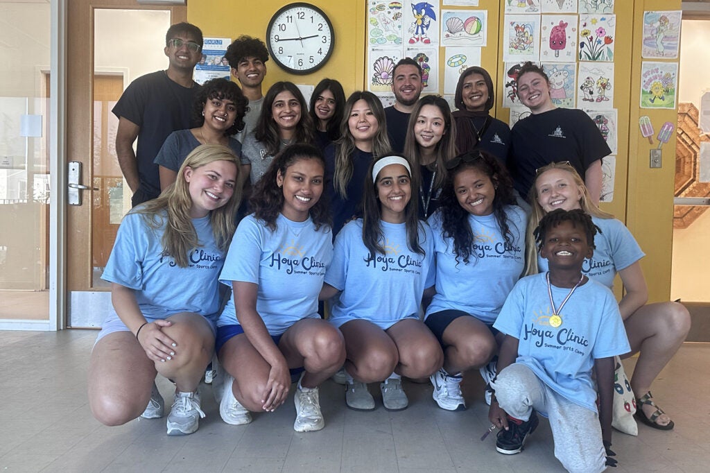 Medical student volunteers and one camper stand together as a group