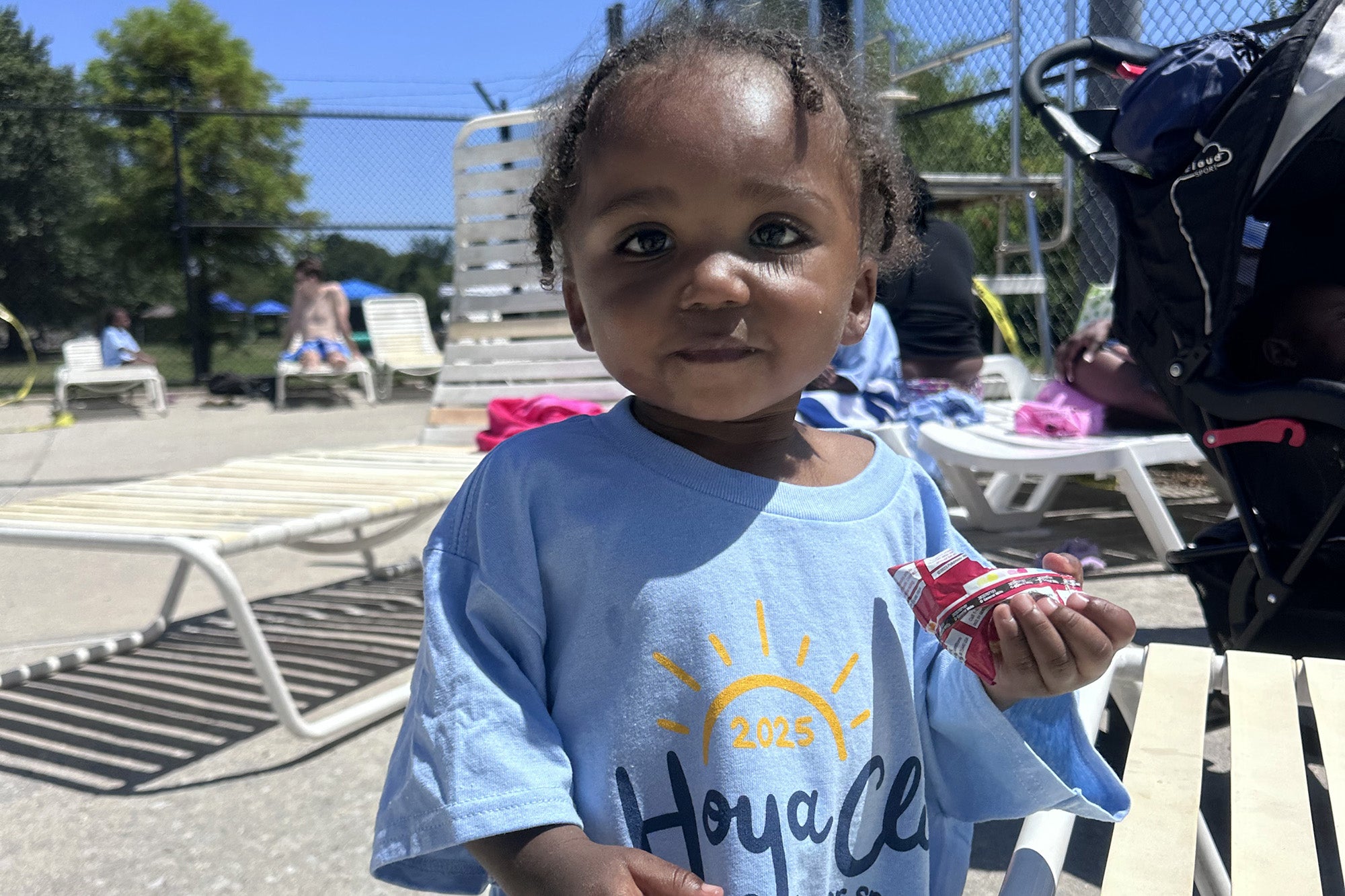 A small girl in Hoya Clinic t-shirt holds a ring pop wrapper and looks at the camera