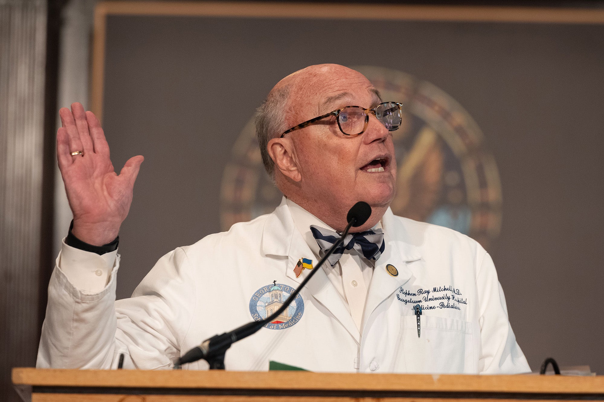 Dean Emeritus Steven Mitchell speaks from a podium and raises his hand