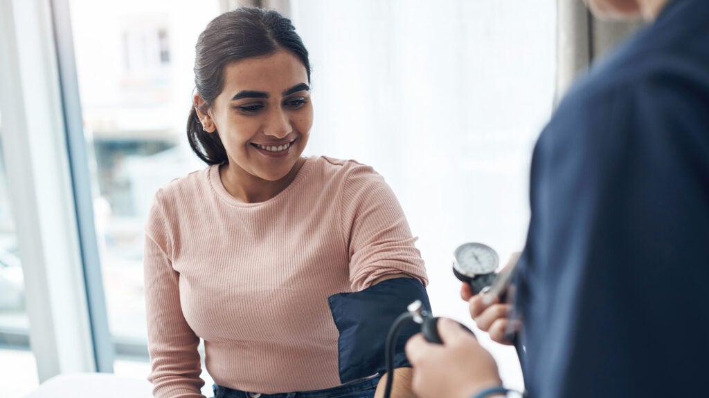 A woman of Hispanic descent has her blood pressure taken by a medical professional