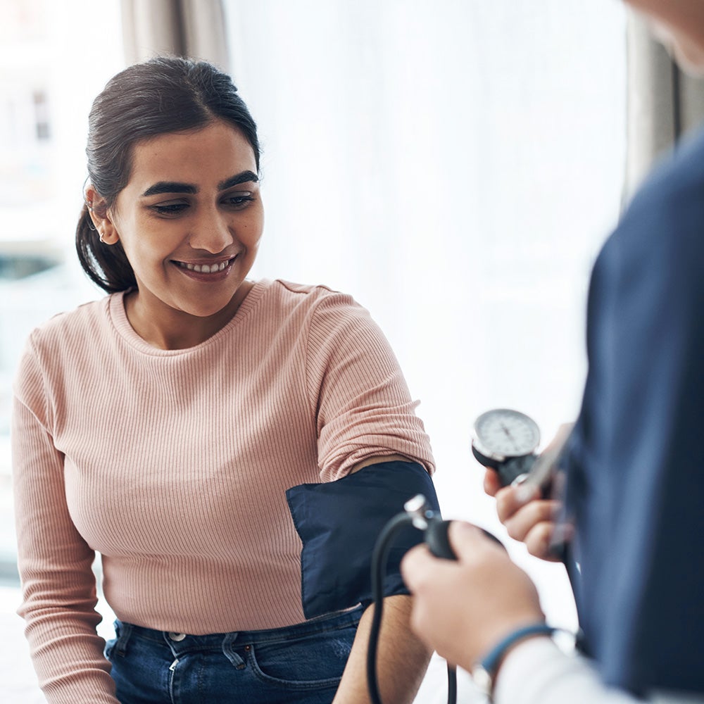 A woman has her blood pressure checked by a medical professional