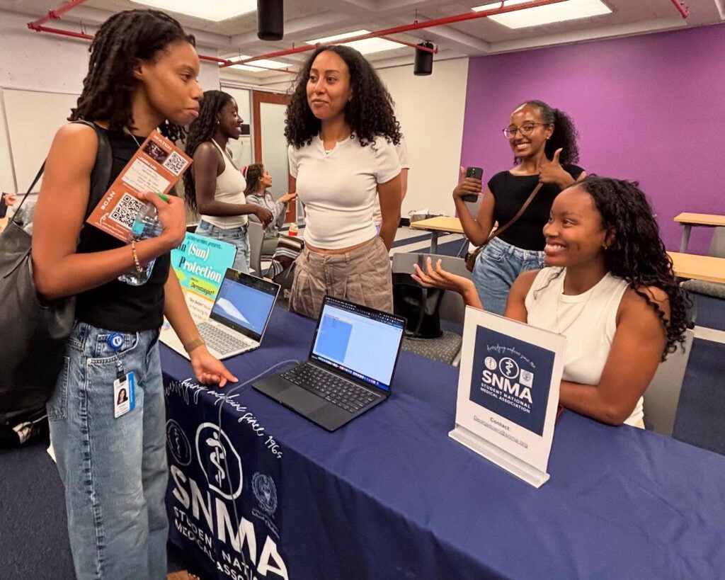 Students interact around a table set up for the SNMA