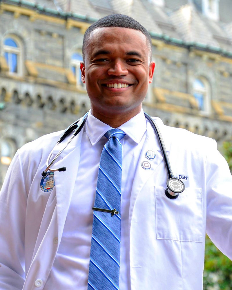 Perry Diaz in white medical coat with Healy Hall in the background