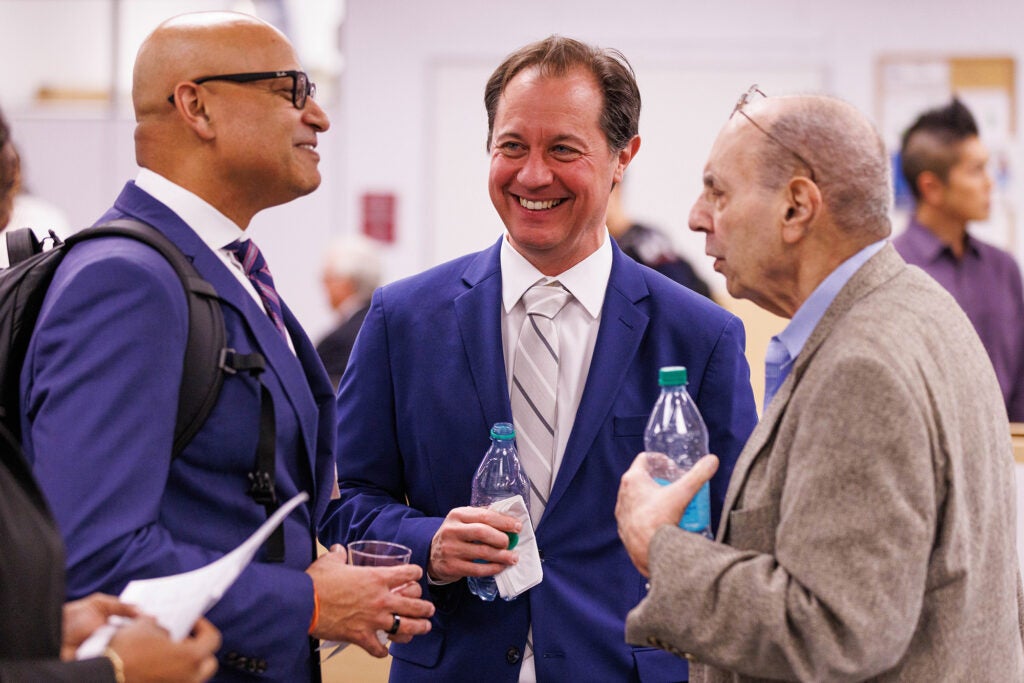 Three men converse in a room