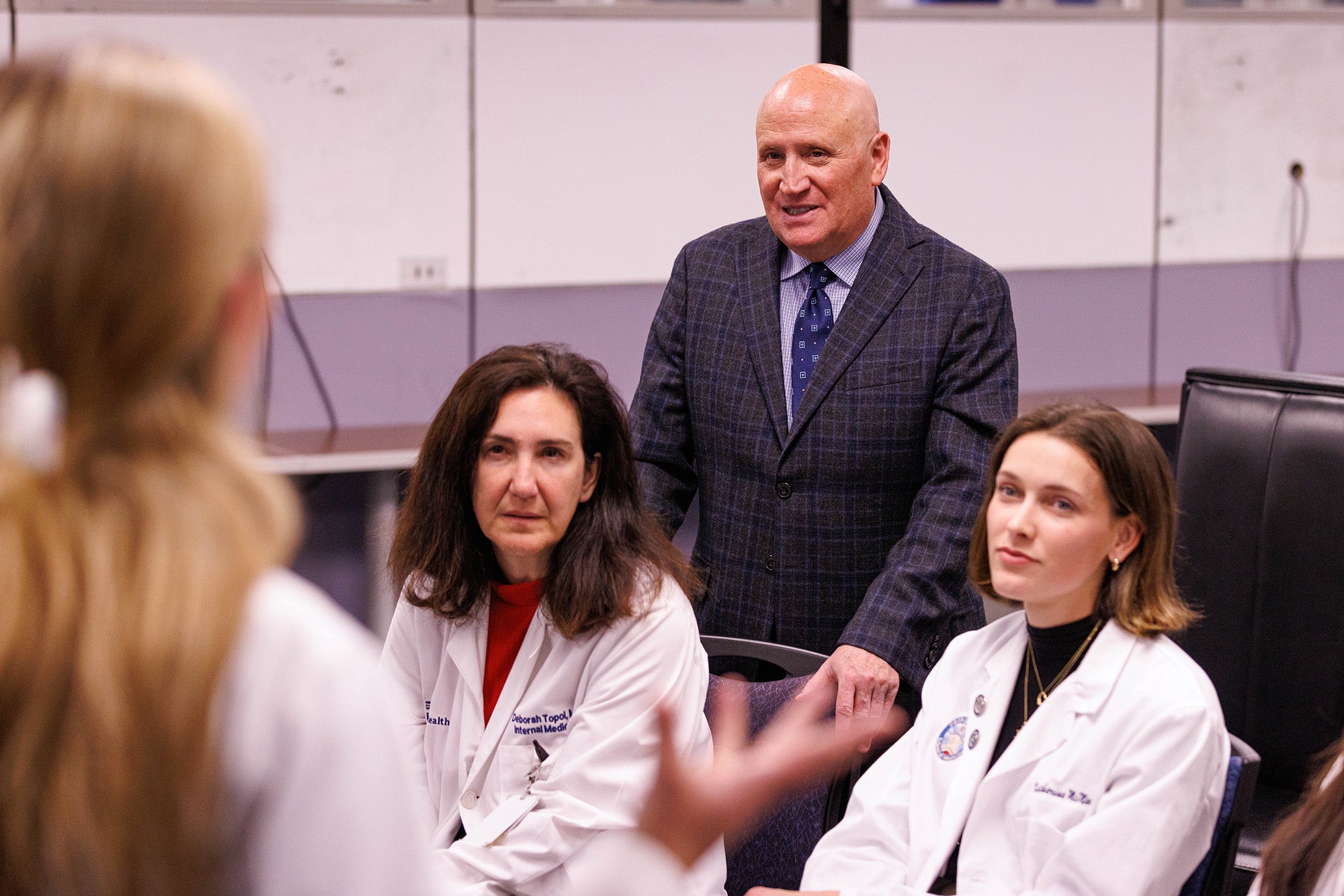 Dr. Timpone, Dr. Topol and a medical student listen as a presenter fields a question.