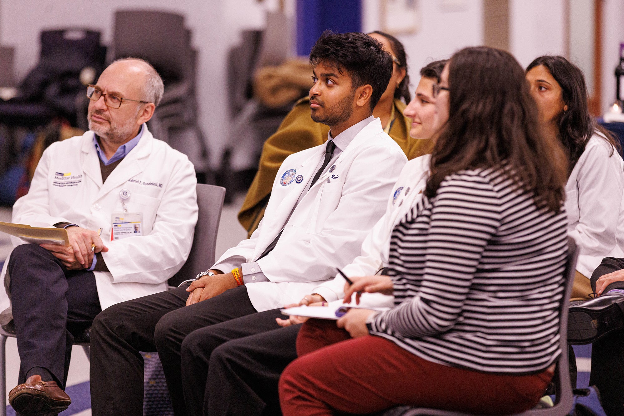 A doctor and several medical students listen to a presentation on Student Research Day