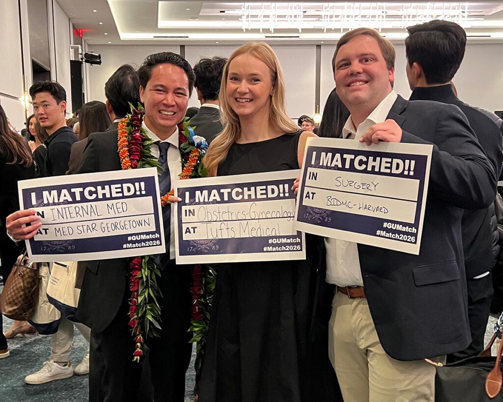 Three students stand together holding their Match Day signs that say where they matched