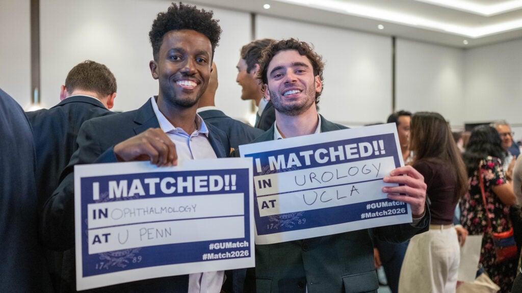 Two males students hold Match Day signs indicating where they matched
