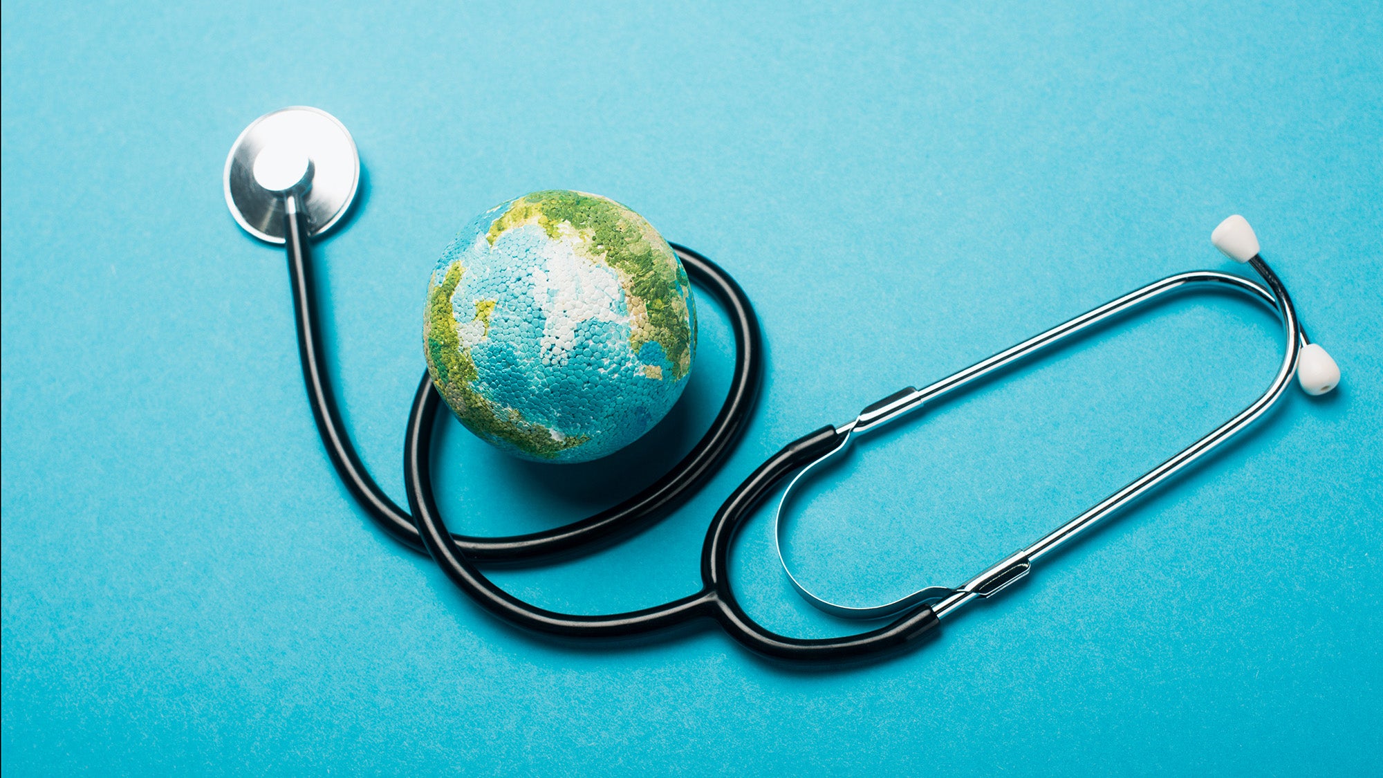 Photo illustration of a small globe model next to a stethoscope