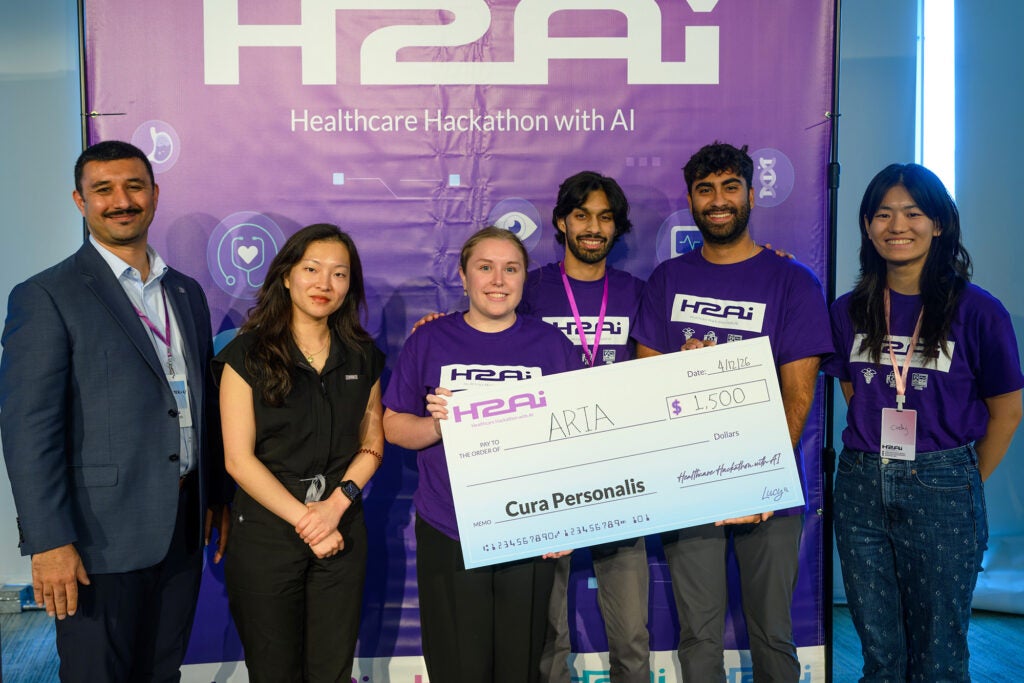 Six individuals stand together with three holding a large award
