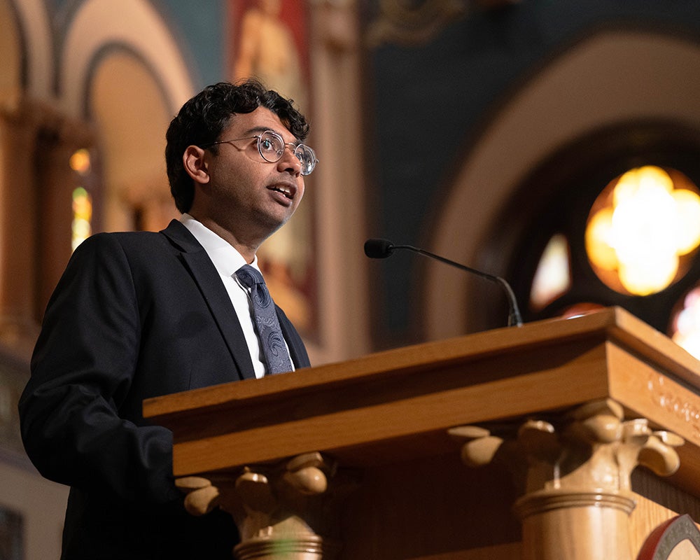 Arjun Mathur speaks from a podium in Gaston Hall