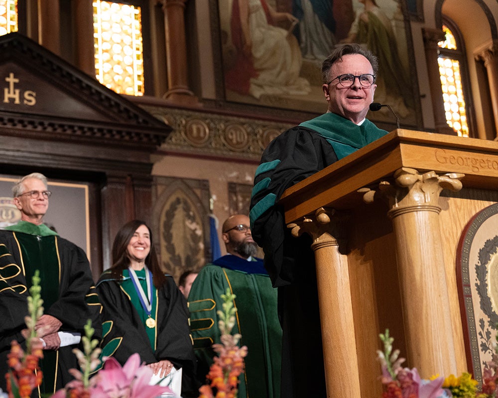 Norman Beauchamp speaks from a podium in Gaston Hall