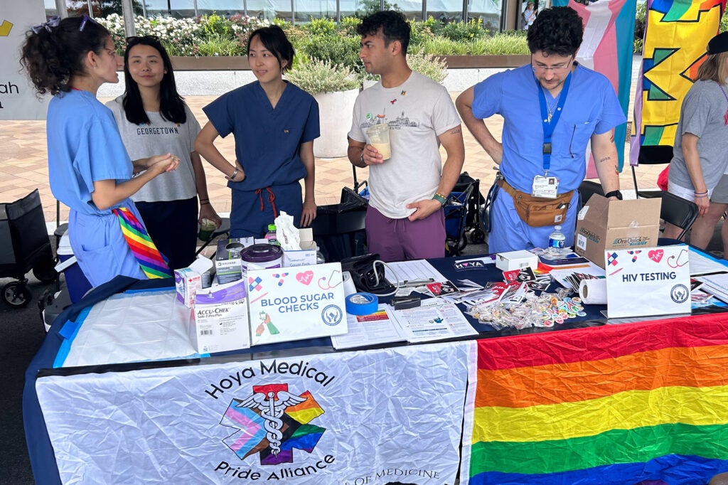 Medical students converse while standing behind their table at the Capital Pride Festival