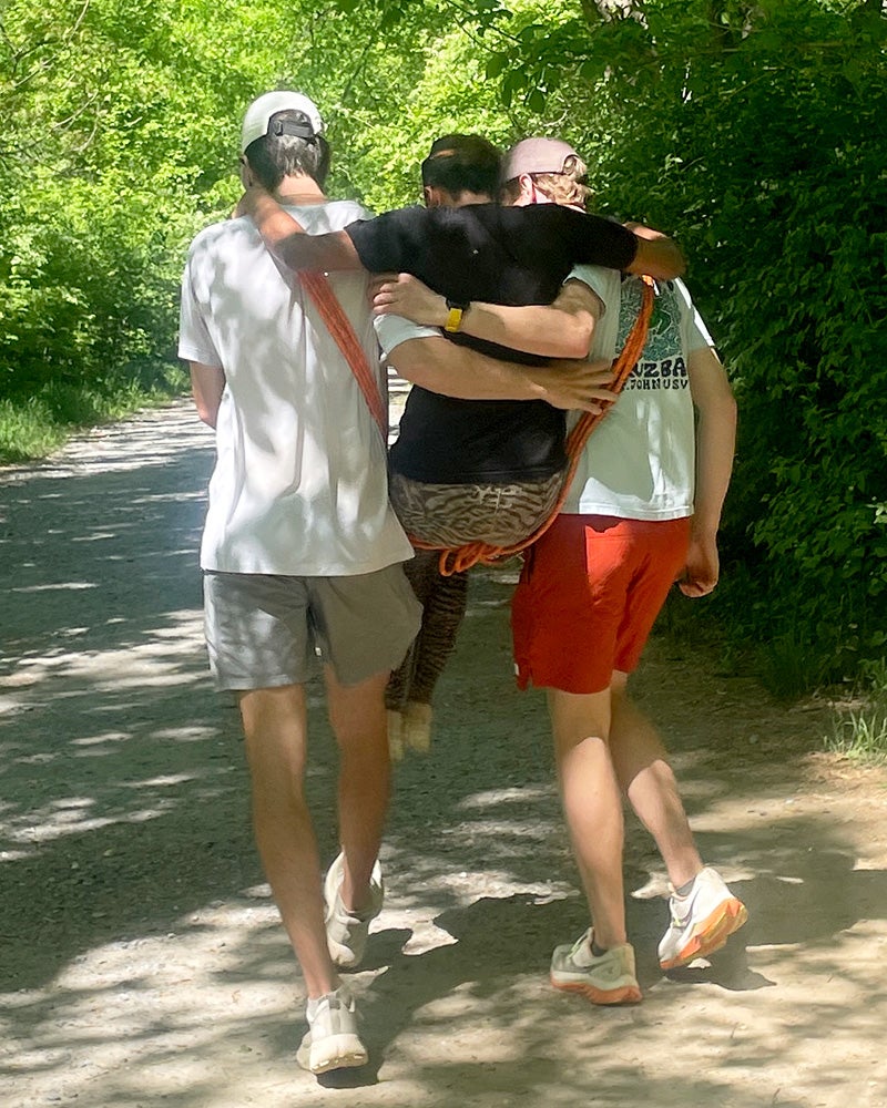Two students carry a third using an improvised sling