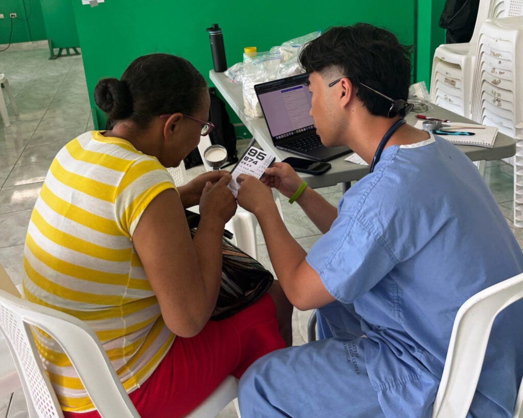 A medical student administers a vision test to a woman
